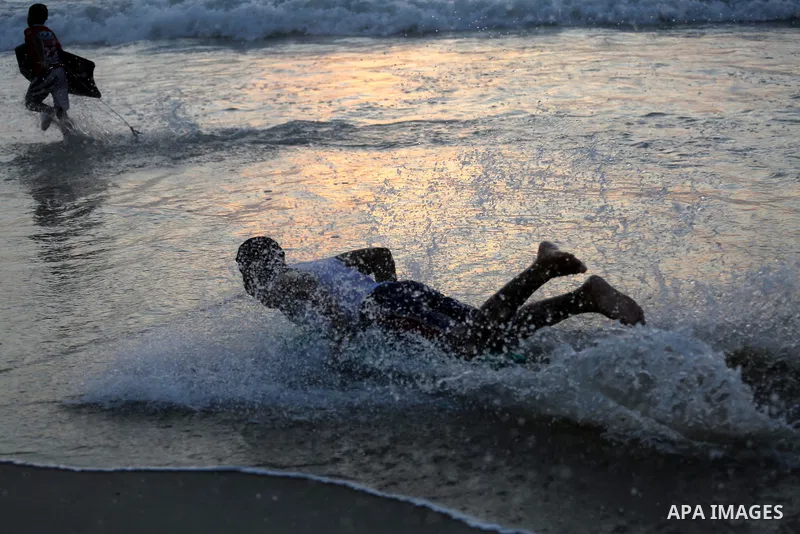 Palestinian youths enjoy a day at the beach of the Mediterranean sea on the coast of Gaza city during sunset, on May 24, 2016. Photo by Mohammed Asad