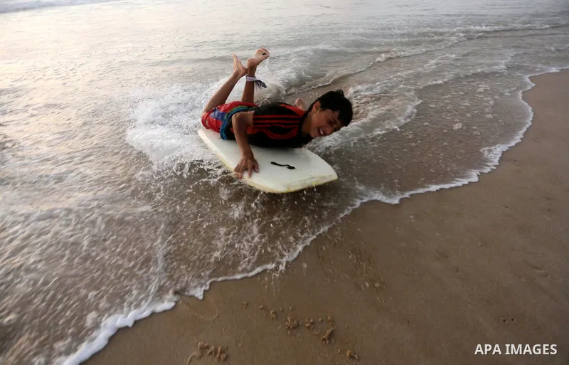 Palestinian youths enjoy a day at the beach of the Mediterranean sea on the coast of Gaza city during sunset, on May 24, 2016. Photo by Mohammed Asad