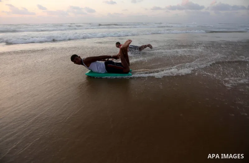 Palestinian youths enjoy a day at the beach of the Mediterranean sea on the coast of Gaza city during sunset, on May 24, 2016. Photo by Mohammed Asad