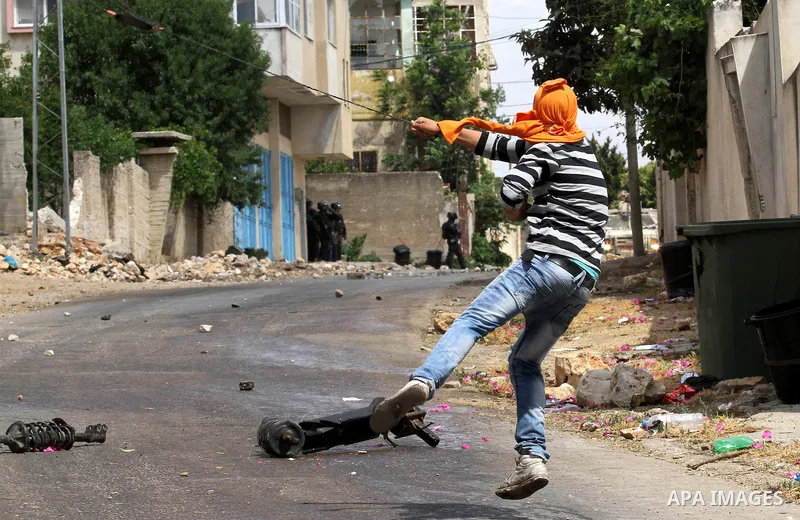 A Palestinian protester uses a slingshot to throw stones towards Israeli security forces during clashes following a demonstration against the expropriation of Palestinian land by Israel, on May 27, 2016 in the village of...