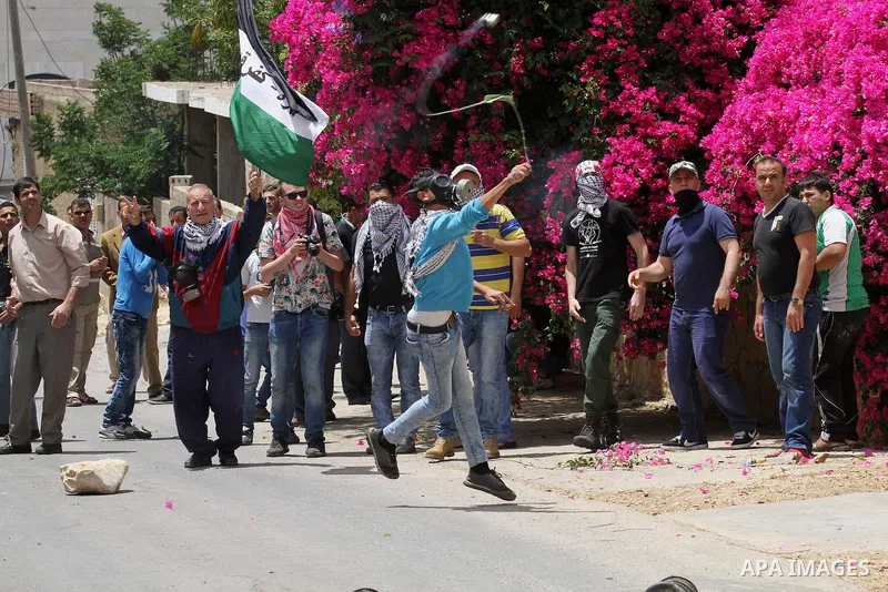 A Palestinian protester uses a slingshot to throw stones towards Israeli security forces during clashes following a demonstration against the expropriation of Palestinian land by Israel, on May 27, 2016 in the village of...