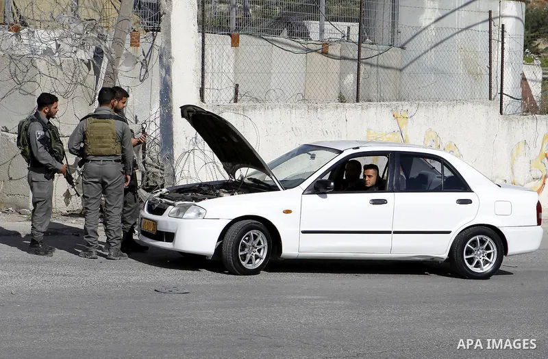 Israeli security forces inspect Palestinian cars in the West Bank village of Halhul, near Hebron, on May 27, 2016. Photo by Wisam Hashlamoun