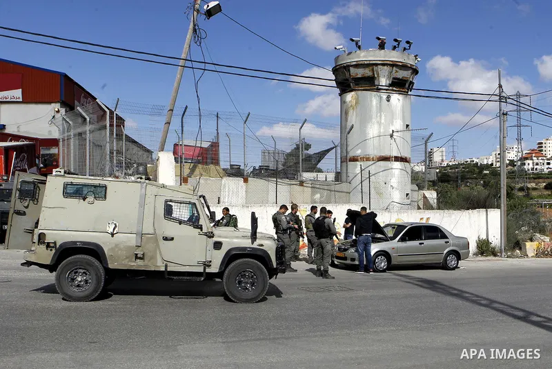 Israeli security forces inspect Palestinian cars in the West Bank village of Halhul, near Hebron, on May 27, 2016. Photo by Wisam Hashlamoun