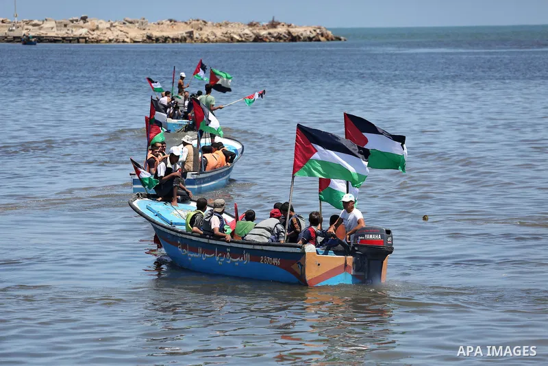 Palestinians hold flags as they ride a boat during a protest to break the siege, at the seaport of Gaza City May 30, 2016. Photo by Mohammed Asad