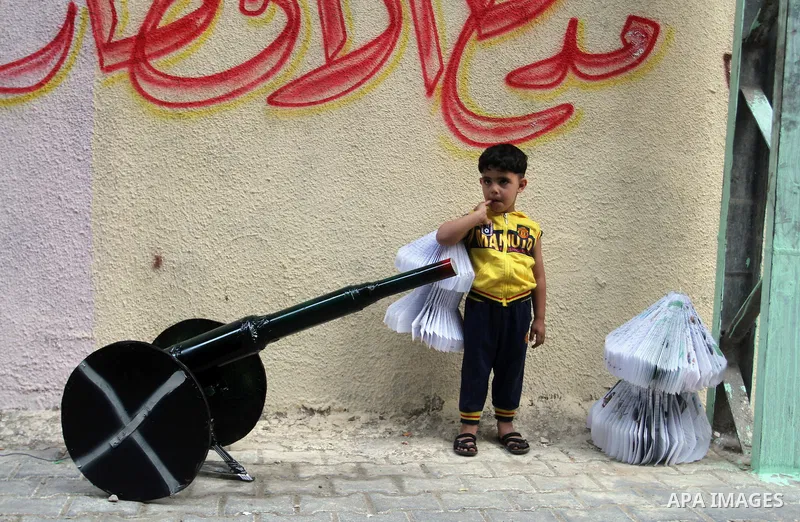 A Palestinian boy holds lantern as he stands next to a cannon of Ramadan that are used during the holy month of Ramadan in the Rafah refugee camp in southern Gaza Strip on May 30, 2016. Photo by Abed Rahim Khatib