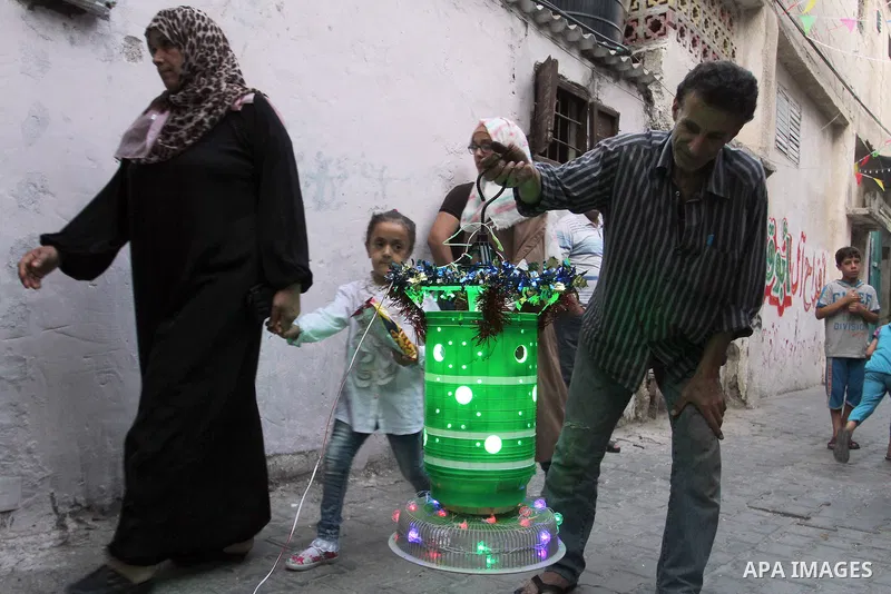Palestinians walks under decorations ahead of the Muslim holy month of Ramadan in the Rafah refugee camp in southern Gaza Strip on May 30, 2016. Photo by Abed Rahim Khatib