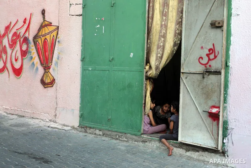 Palestinian children stand outside their house during hang up decorations before the holy month of Ramadan in the Rafah refugee camp in southern Gaza Strip on May 30, 2016. Photo by Abed Rahim Khatib