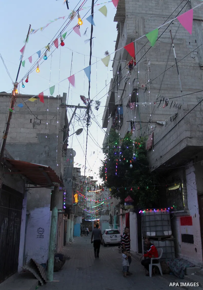 Palestinians walks under decorations ahead of the Muslim holy month of Ramadan in the Rafah refugee camp in southern Gaza Strip on May 30, 2016. Photo by Abed Rahim Khatib