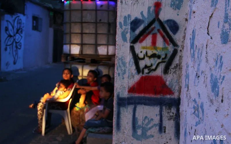 Palestinian children stand outside their house during hang up decorations before the holy month of Ramadan in the Rafah refugee camp in southern Gaza Strip on May 30, 2016. Photo by Abed Rahim Khatib