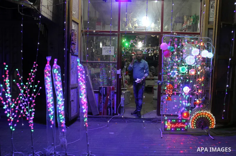 Palestinian man stand outside his shop during hang up decorations before the holy month of Ramadan in the Rafah refugee camp in southern Gaza Strip on May 30, 2016. Photo by Abed Rahim Khatib