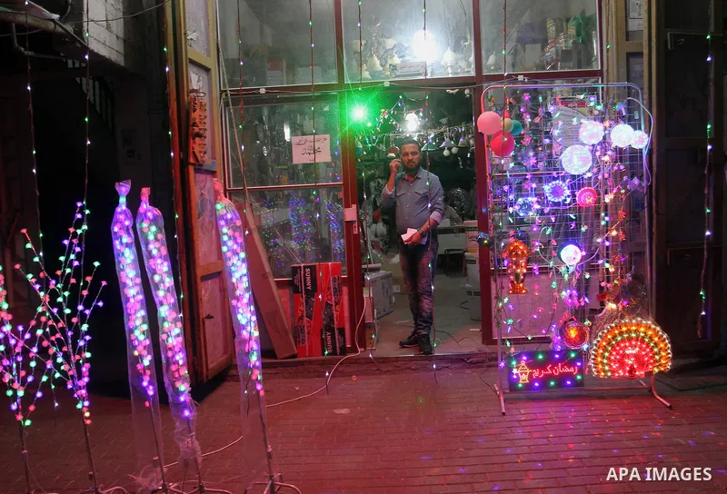 Palestinian man stand outside his shop during hang up decorations before the holy month of Ramadan in the Rafah refugee camp in southern Gaza Strip on May 30, 2016. Photo by Abed Rahim Khatib