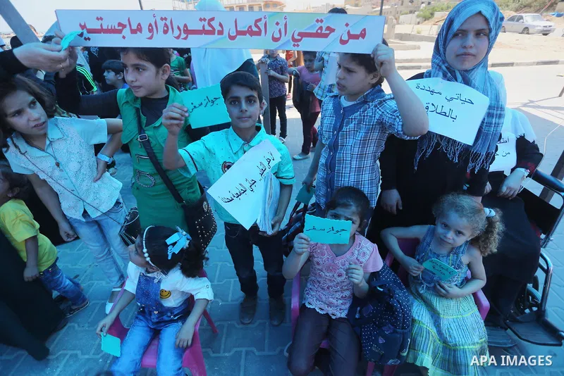 Palestinian children hold banners during a protest to break the siege, at the seaport of Gaza City on 01 June 2016. Photo by Mohammed Asad