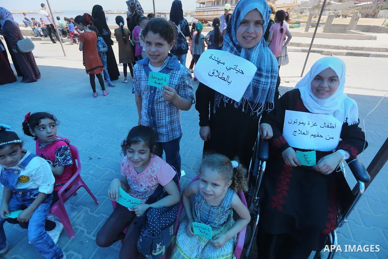 Palestinian children hold banners during a protest to break the siege, at the seaport of Gaza City on 01 June 2016. Photo by Mohammed Asad
