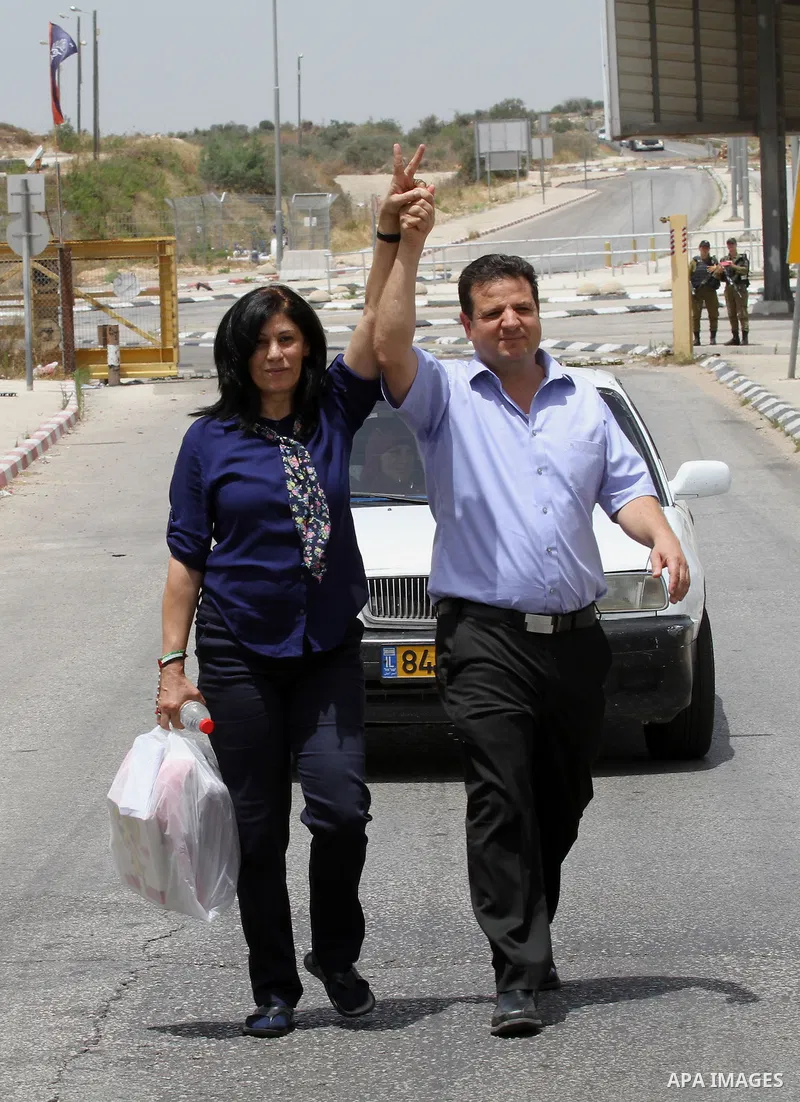 Prominent Palestinian lawmaker Khalida Jarrar walks flashing the sign for victory and holding the hand of the head of Israel's Arab parliamentary bloc Ayman Odeh as she walks through Jubara checkpoint near the northern W...