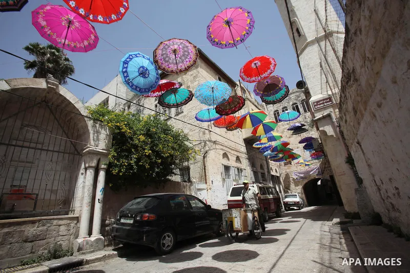 Palestinians walk under show umbrellas used to decorate a street in the Old City of the West Bank town of Nablus, on June 5, 2016 as the faithful prepare to start fasting month of Ramadan. More than 1.5 billion Muslims a...