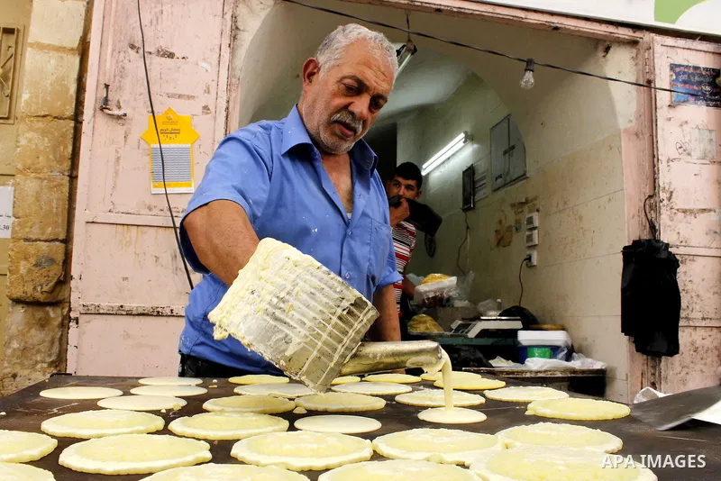A Palestinian man prepares traditional pancakes known as ''Qatayef'' at market in the Old City of the West Bank town of Hebron, on June 5, 2016 as the faithful prepare to start fasting month of Ramadan. More than 1.5 bil...