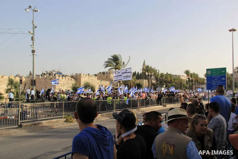 Israelis wave their country's national flags as they take part in an annual march marking Israel's 1967 seizure of the Palestinian-dominated eastern half of Jerusalem, outside Damascus Gate in Jerusalem's old city on Jun...