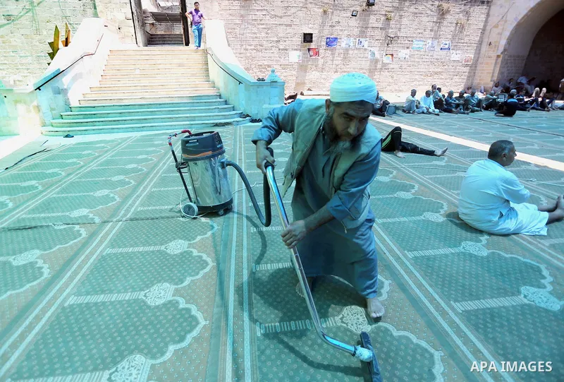 A Palestinian Man cleans insaide the Omari Mosque in Gaza City on June 6, 2016, on the first day of the holy month of Ramadan. Photo by Mohammed Asad
