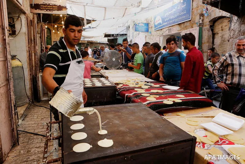 A Palestinian man prepares traditional pancakes known as ''Qatayef'' at market on the first day of the Ramadan in the Old City of the West Bank town of Hebron, on June 6, 2016 as the faithful prepare to start fasting mon...