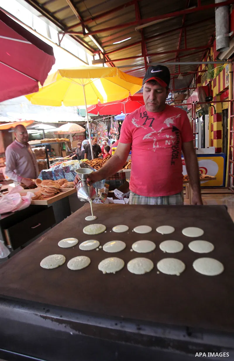 A Palestinian man prepares traditional pancakes known as ''Qatayef'' on the holy month of Ramadan at market in the Old City of the West Bank town of Nablus, on June 7, 2016. Ramadan is sacred to Muslims because it is dur...