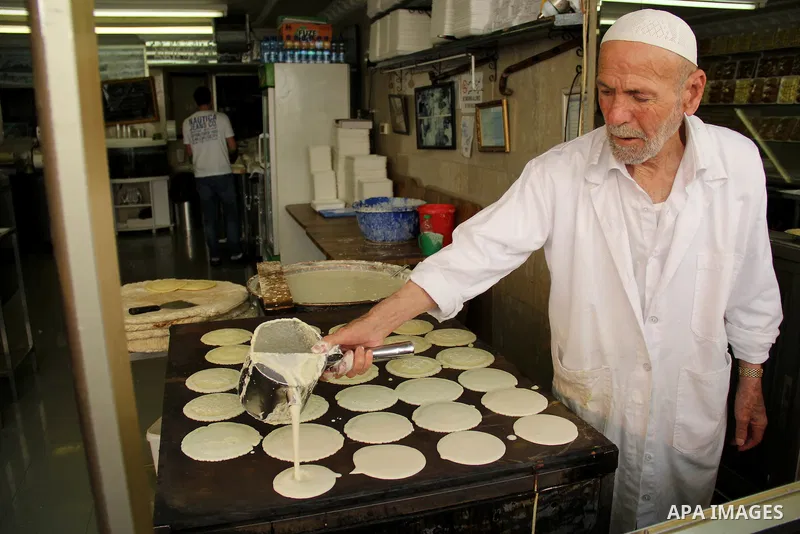 A Palestinian man prepares traditional pancakes known as ''Qatayef'' on the holy month of Ramadan at a market in Jerusalem's old city on June 7, 2016. Ramadan is sacred to Muslims because it is during that month that tra...