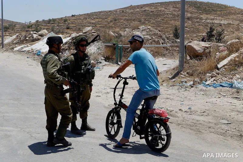 Israeli soldiers stop a Palestinian on his bicycle at the entrance of Yatta near the West Bank city of Hebron June 9, 2016. The Israeli army entered the village in search for clues leading to an attack the previous night...