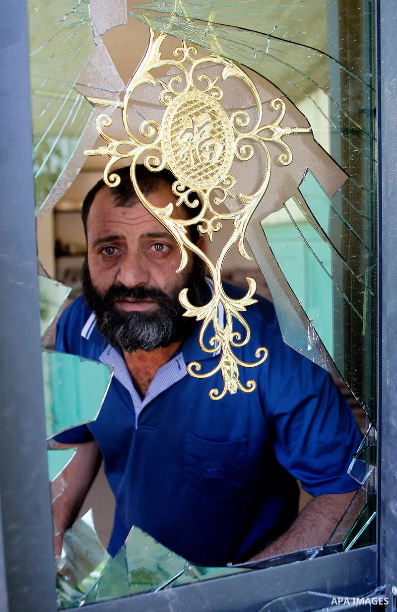 A Palestinian man looks through a window as Israeli soldiers stand guard at the entrance of Yatta near the West Bank city of Hebron June 9, 2016. The Israeli army entered the village in search for clues leading to an att...