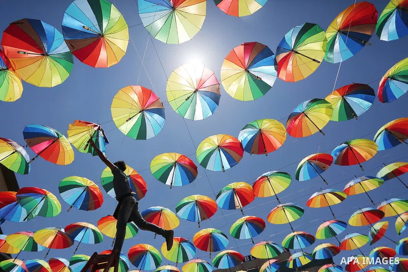 A Palestinian worker of a beachside café shop decorates its terrace with hanging colourful umbrellas as part of decorations for the Muslim holy fasting month of Ramadan in Gaza City, on June 9, 2016. Ramadan is sacred to...
