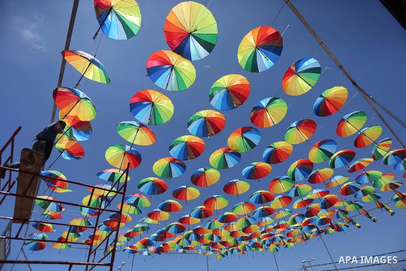 A Palestinian worker of a beachside café shop decorates its terrace with hanging colourful umbrellas as part of decorations for the Muslim holy fasting month of Ramadan in Gaza City, on June 9, 2016. Ramadan is sacred to...