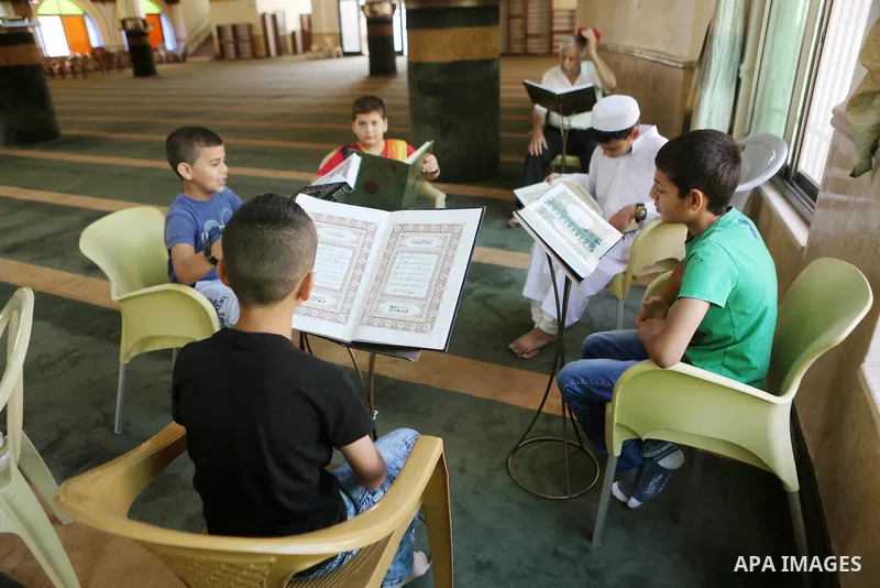 Palestinian Muslim children read the holy Koran, Islam's holy book at Tameem al-Dari mosque on the holy month of Ramadan in the West bank city of Ramallah, on June 09, 2016. Ramadan is sacred to Muslims because it is dur...