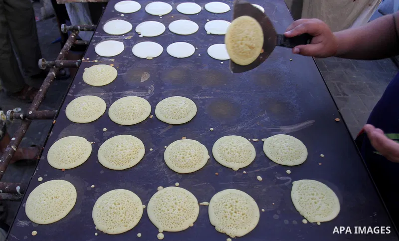 A Palestinian man prepares traditional pancakes known as ''Qatayef at a market during the Muslim holy fasting month of Ramadan in Rafah in the southern Gaza strip, on June 9, 2016. Photo by Abed Rahim Khatib