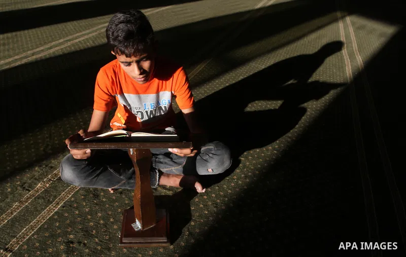 A Palestinian boy reads the holy Koran, Islam's holy book, at a Mosque during the Muslim holy fasting month of Ramadan in Rafah in the southern Gaza strip, on June 9, 2016. Photo by Abed Rahim Khatib