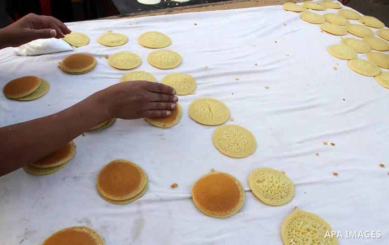A Palestinian man prepares traditional pancakes known as ''Qatayef at a market during the Muslim holy fasting month of Ramadan in Rafah in the southern Gaza strip, on June 9, 2016. Photo by Abed Rahim Khatib