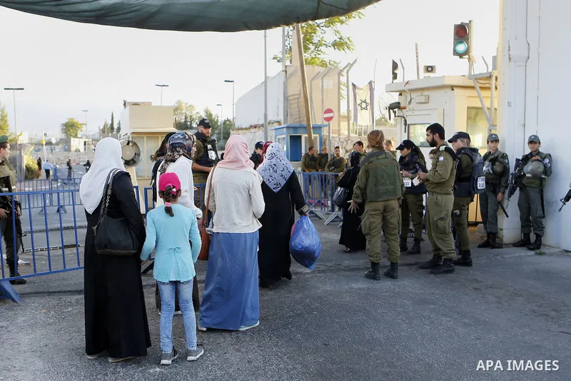 Palestinians walk to the Israeli checkpoint between the West Bank town of Bethlehem and Jerusalem, as Palestinians wait to cross to Jerusalem to attend the first Friday noon prayers of the holy Muslim fasting month of Ra...