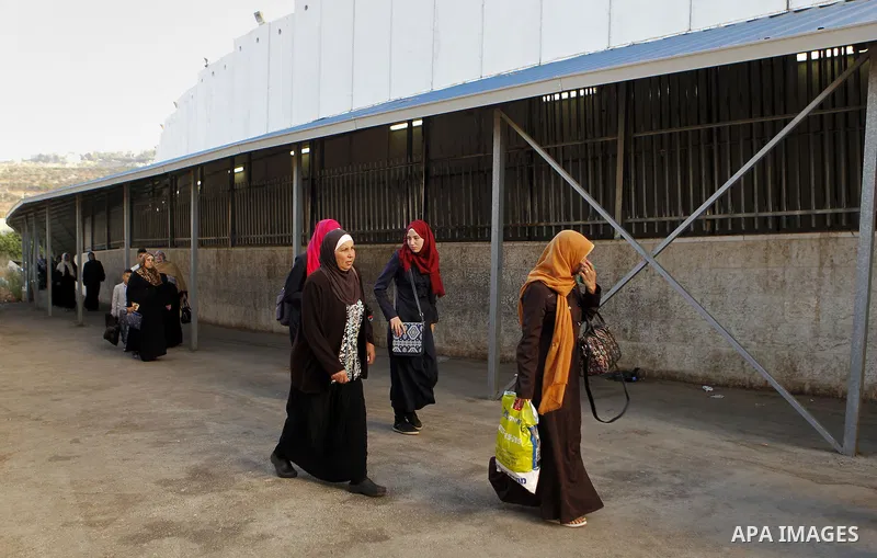 Palestinians walk to the Israeli checkpoint between the West Bank town of Bethlehem and Jerusalem, as Palestinians wait to cross to Jerusalem to attend the first Friday noon prayers of the holy Muslim fasting month of Ra...