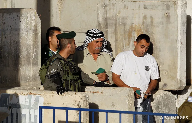 Israeli border police check the identity card of a Palestinian at an Israeli checkpoint as he makes his way to attend the first Friday prayer of the holy fasting month of Ramadan in Jerusalem's al-Aqsa mosque, in the Wes...