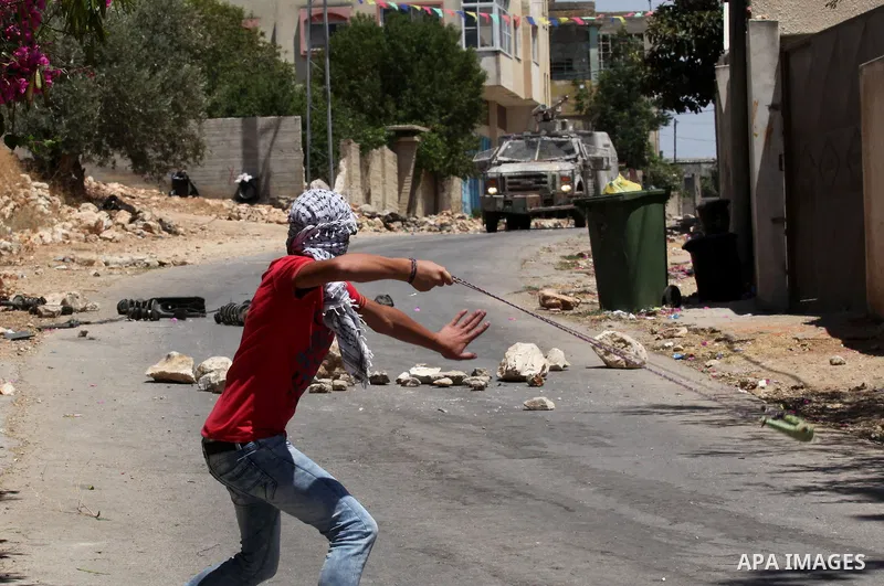 A Palestinian protester uses a slingshot to throw stones towards Israeli security forces during clashes following a demonstration against the expropriation of Palestinian land by Israel, on June 10, 2016. in the village...