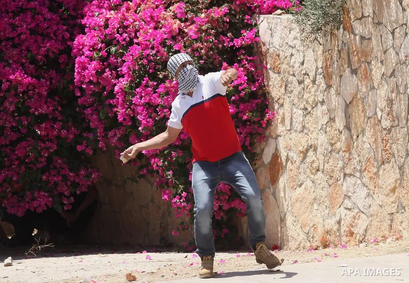 A Palestinian protester uses a slingshot to throw stones towards Israeli security forces during clashes following a demonstration against the expropriation of Palestinian land by Israel, on June 10, 2016. in the village...