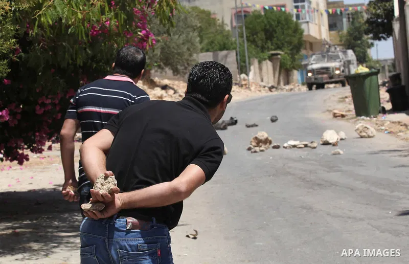 Palestinian protesters hurl stones at an Israeli soldier during clashes after a protest against the expanding of Jewish settlements in a village near the West Bank city of Nablus, on June 10, 2016. Photo by Nedal Eshtaya...