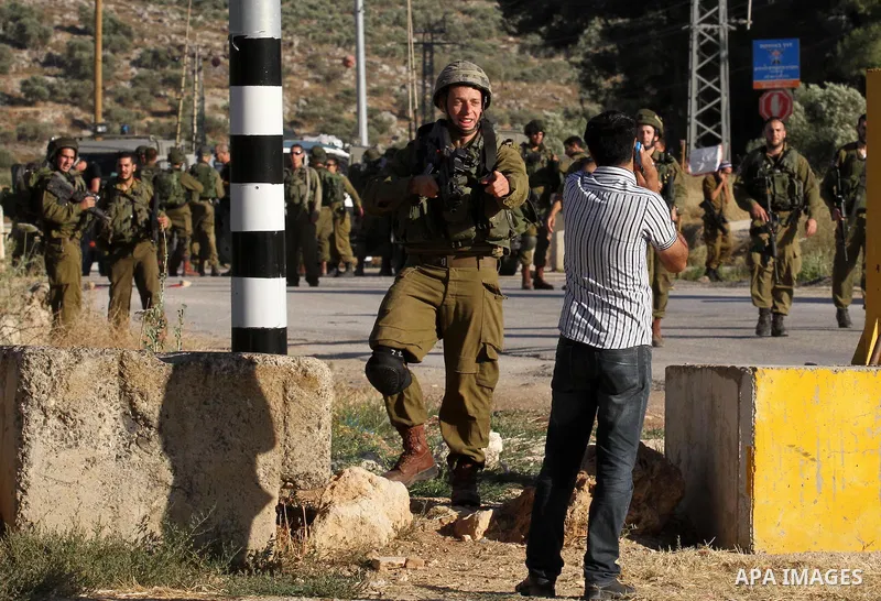 Israeli security forces argue with a Palestinian at a checkpoint near the West Bank city of Nablus, June 10, 2016, after a Palestinian man attempted a stabbing attack. Palestinian was shot and wounded, army said. Photo b...