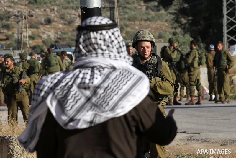 Israeli security forces argue with a Palestinian at a checkpoint near the West Bank city of Nablus, June 10, 2016, after a Palestinian man attempted a stabbing attack. Palestinian was shot and wounded, army said. Photo b...