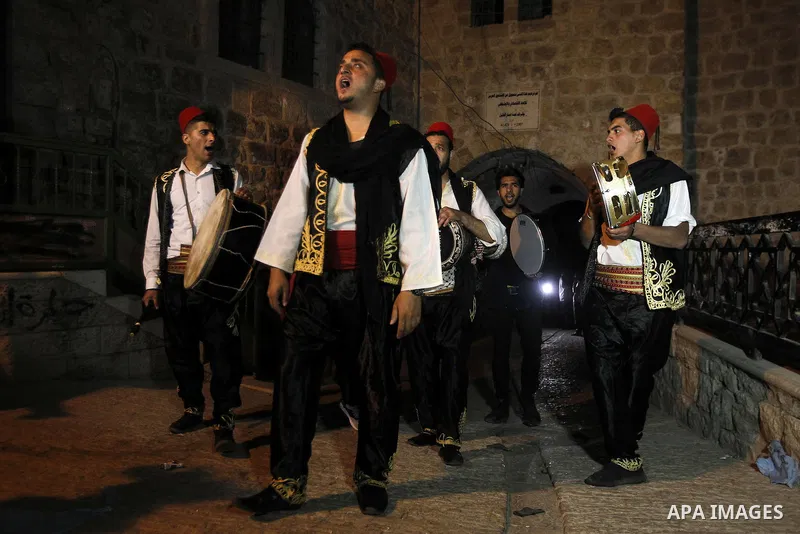 Palestinians dawn awakener "al-Musaharati" walk through streets to wake up Muslims for a meal before sunrise during the fasting month of Ramadan, in the West Bank city of Hebron city on June 12, 2016. Al-Musaharati is an...