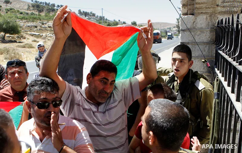 A Palestinian protester holds a sign as he argues with an Israeli army soldier during a protest against what organisers say is land confiscation by Israel, near Arroub refugee camp north of the West Bank city of Hebron J...