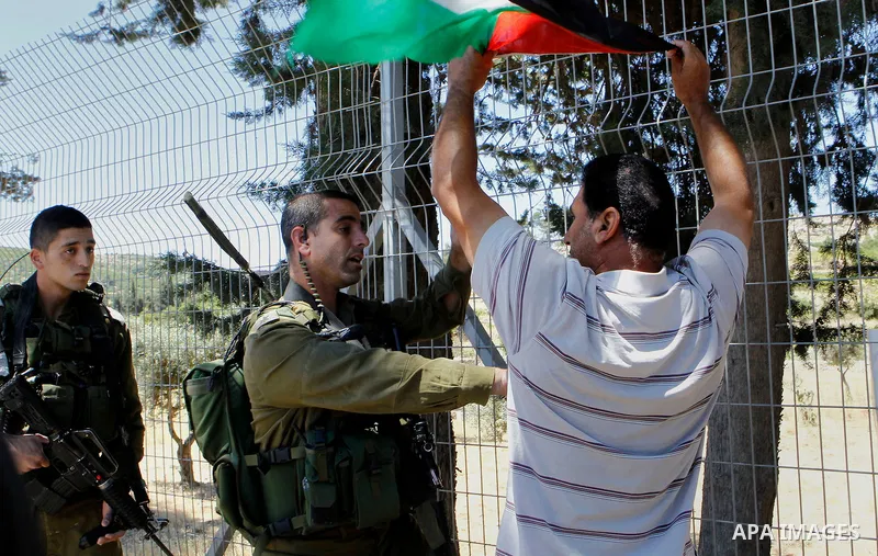 A Palestinian protester holds a sign as he argues with an Israeli army soldier during a protest against what organisers say is land confiscation by Israel, near Arroub refugee camp north of the West Bank city of Hebron J...