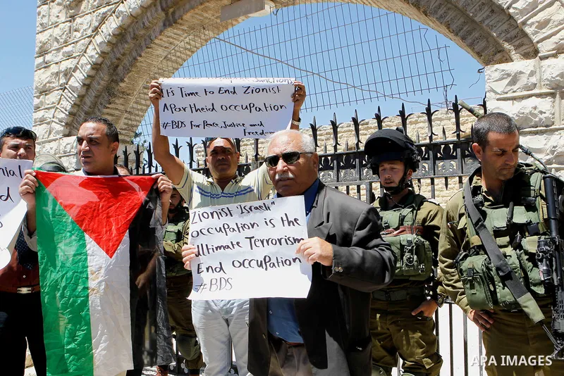 Palestinian protesters hold banners during a protest against what organisers say is land confiscation by Israel, near Arroub refugee camp north of the West Bank city of Hebron June 12, 2016. Photo by Wisam Hashlamoun