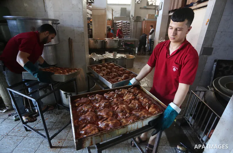 Palestinians prepare rice and meats as they wait for customers several hours before Iftar, the breaking of the day long Ramadan fast in Gaza City, on June 12, 2016. Muslims around the world refrain from eating, drinking...