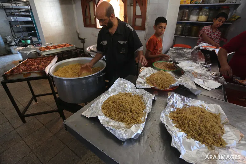 Palestinians prepare rice and meats as they wait for customers several hours before Iftar, the breaking of the day long Ramadan fast in Gaza City, on June 12, 2016. Muslims around the world refrain from eating, drinking...