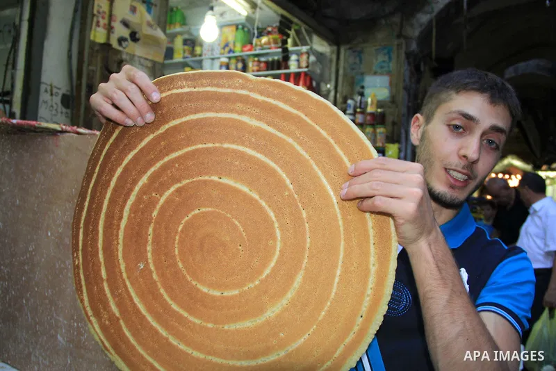 A Palestinian man prepares traditional pancakes known as ''Qatayef" at a market during the Muslim holy fasting month of Ramadan in Jerusalem's old city on June, 12, 2016. Ramadan is sacred to Muslims because it is during...