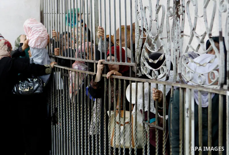 Palestinian families carry containers as they wait to receive free food for 'Iftar', the meal that breaks the daily fast during Ramadan in the West Bank city of Hebron, 13 June 2016. the "Ibrahimi Takiya" was founded in...