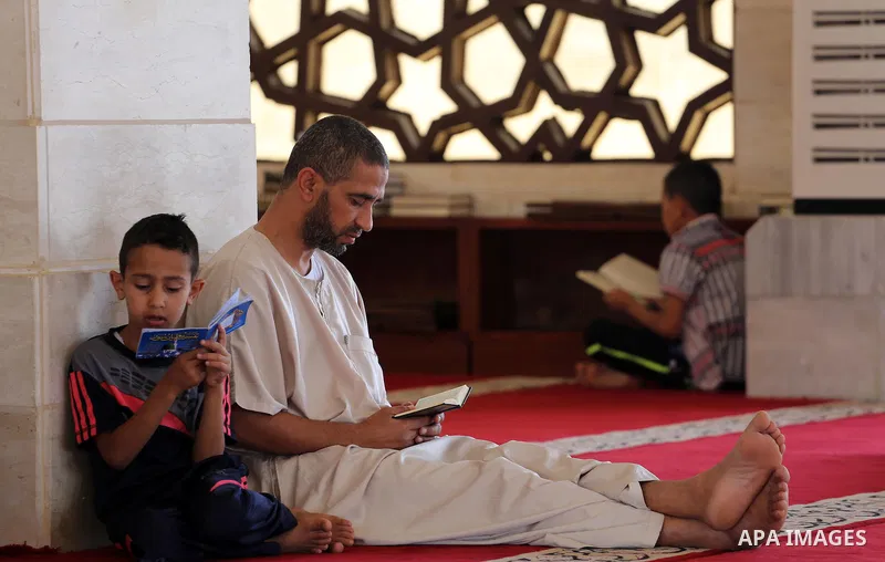 Palestinian men sit reading the Koran, Islam's holy book, at the al-Khaldi mosque during the Muslim fasting month of Ramadan, in Gaza City on June 13, 2016. Photo by Mohammed Asad
